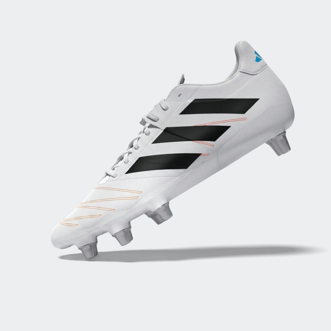 White Adidas Kakari Elite SG rugby boot with black stripes and orange stitching details, viewed from the side.