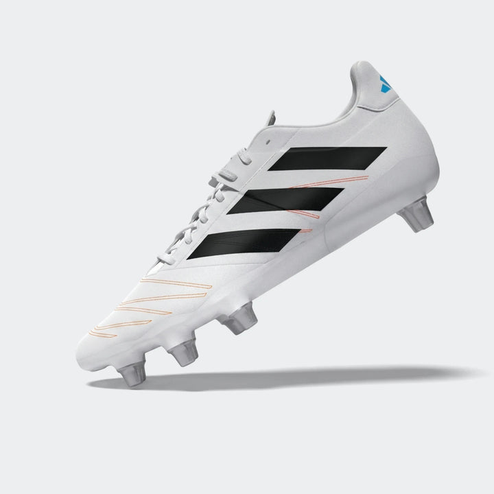 White Adidas Kakari Elite SG rugby boot with black stripes and orange stitching details, viewed from the side.