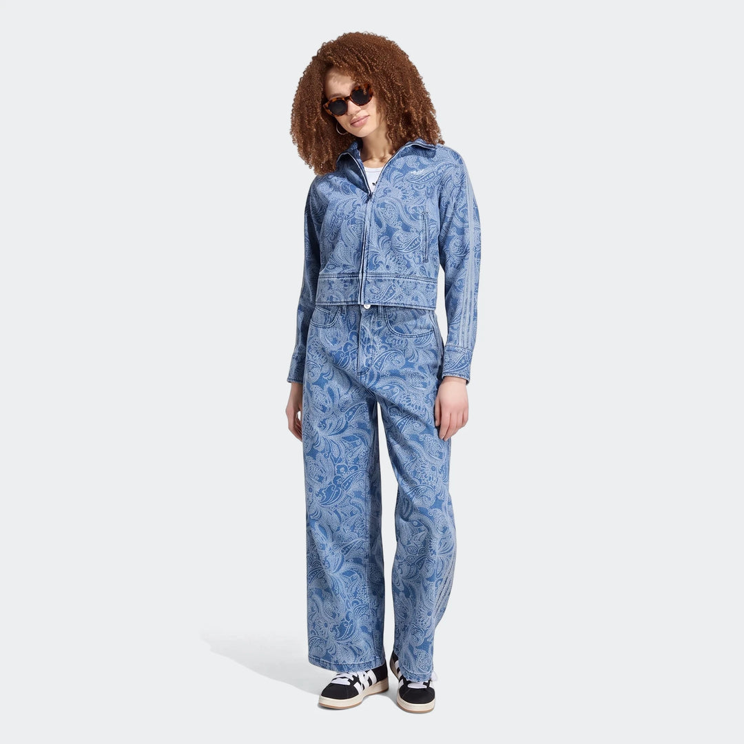 Full body shot of a model wearing the Adidas Liberty London Firebird denim tracktop and matching wide-leg pants with paisley