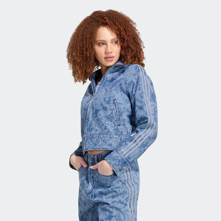 Model wearing an Adidas Liberty London Firebird blue denim tracktop and matching pants with a white paisley pattern.