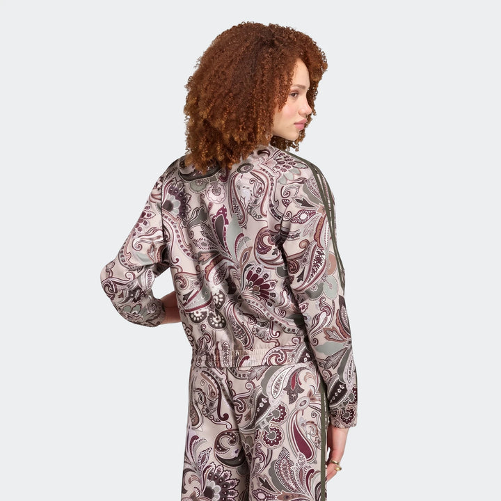Woman wearing Adidas Liberty London Firebird Satin Track Top and matching paisley print pants, viewed from the back.