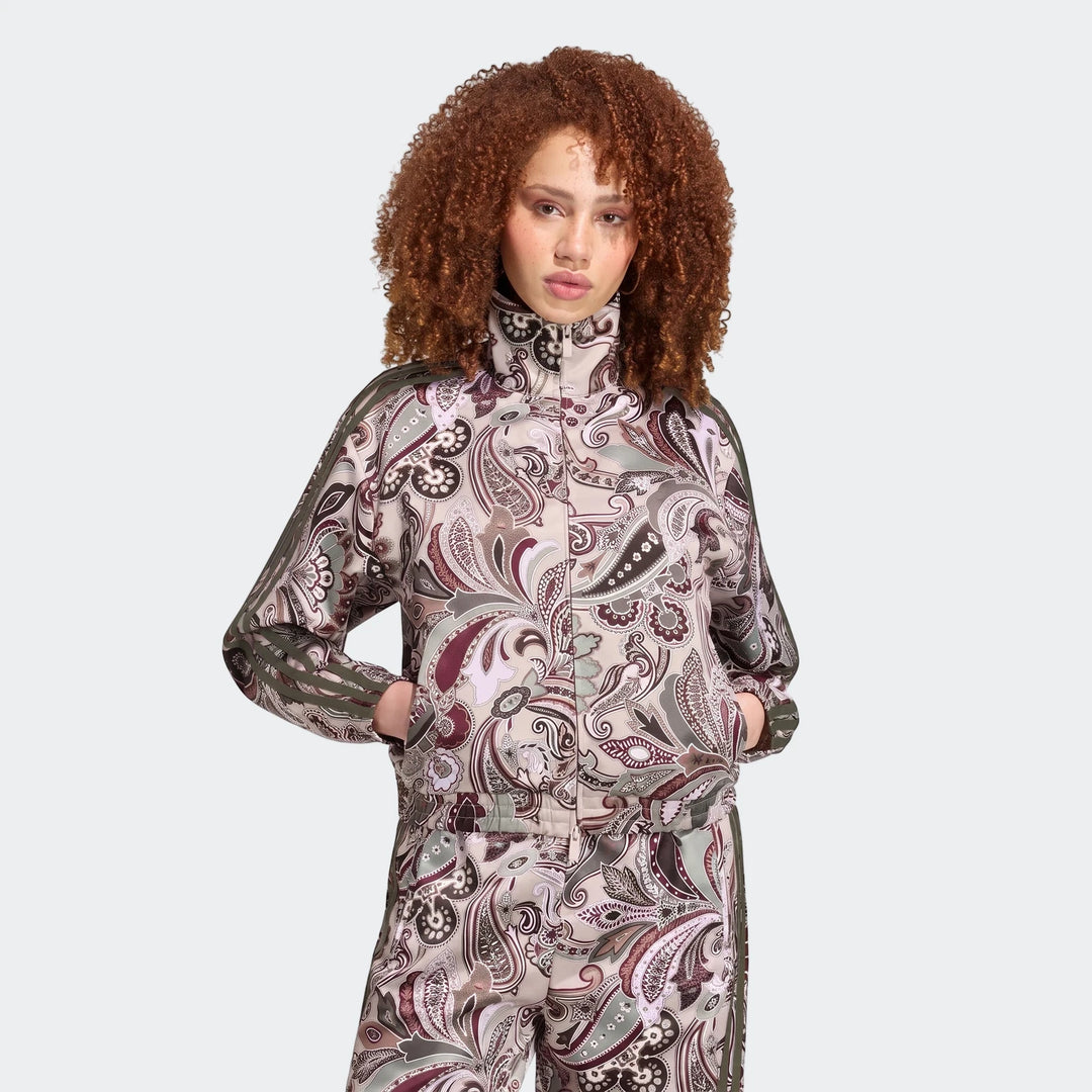 Woman wearing an Adidas Liberty London Firebird Satin Track Top and matching pants with a beige paisley print