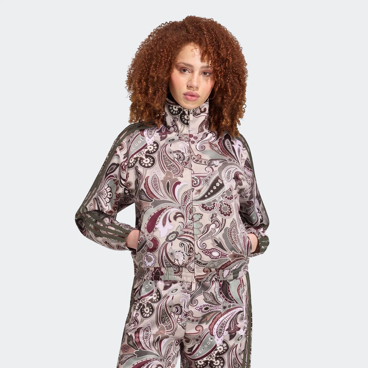 Woman wearing an Adidas Liberty London Firebird Satin Track Top and matching pants with a beige paisley print
