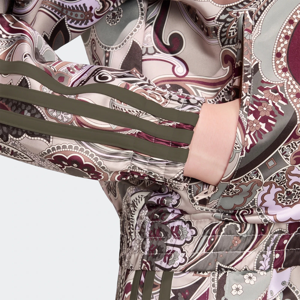 Close-up of an Adidas Liberty London Firebird Satin Track Top featuring an intricate paisley pattern and dark olive stripes,