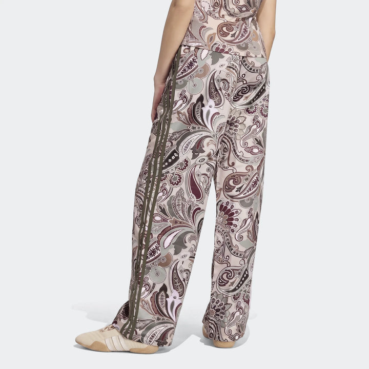 Adidas Liberty London Firebird Satin Trackpants with paisley print and olive green side stripes, shown from a back view on a