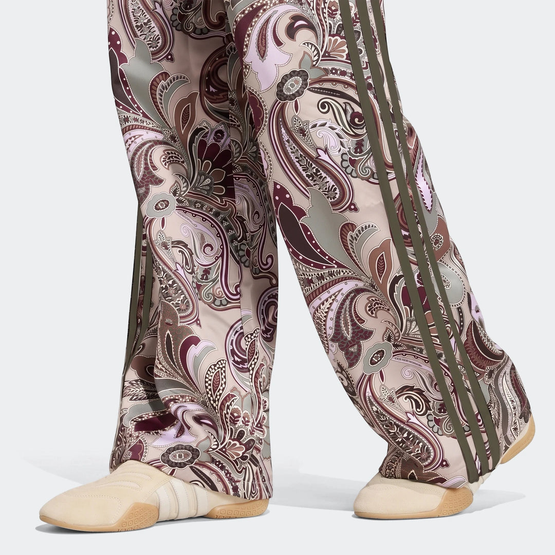 Adidas Liberty London Firebird Satin Trackpant with a vibrant paisley pattern, paired with cream sneakers.