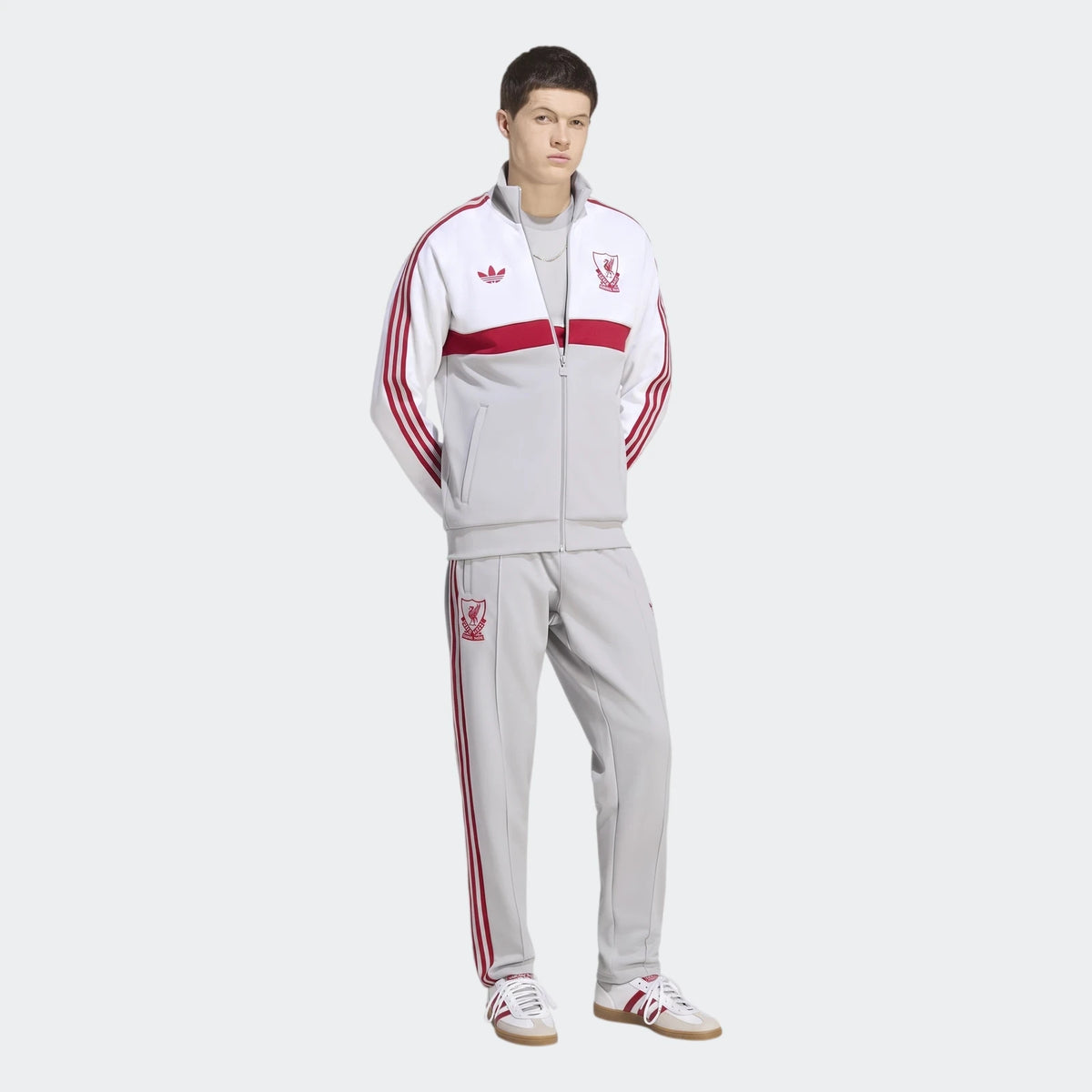Male model wearing a full white, red, and grey Adidas Liverpool FC Originals Track Top and matching track pants, paired with
