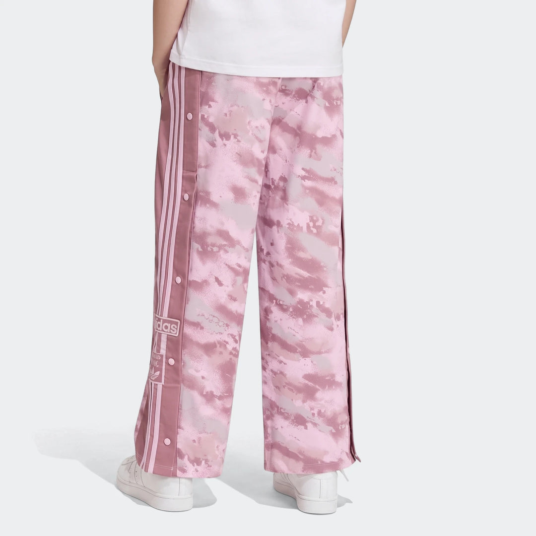 Loose Adibreak Camo Twill Trousers in pink camouflage, featuring side snap buttons and three stripes, worn by a person from