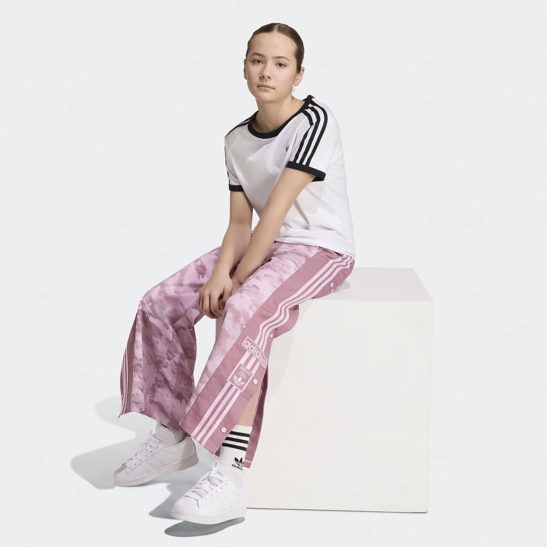 Young female model wearing pink camouflage Adidas Loose Adibreak Camo Twill Trousers with a white t-shirt and white