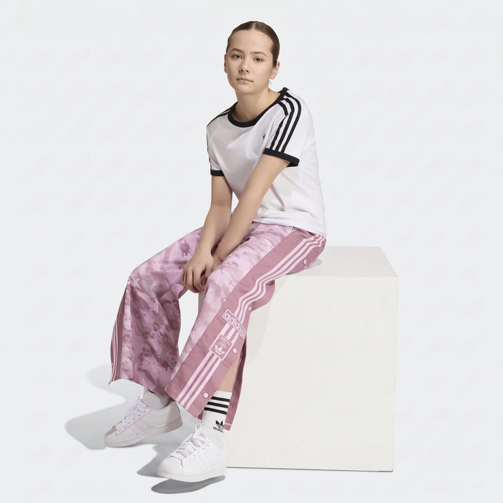 Young female model wearing pink camouflage Adidas Loose Adibreak Camo Twill Trousers with a white t-shirt and white