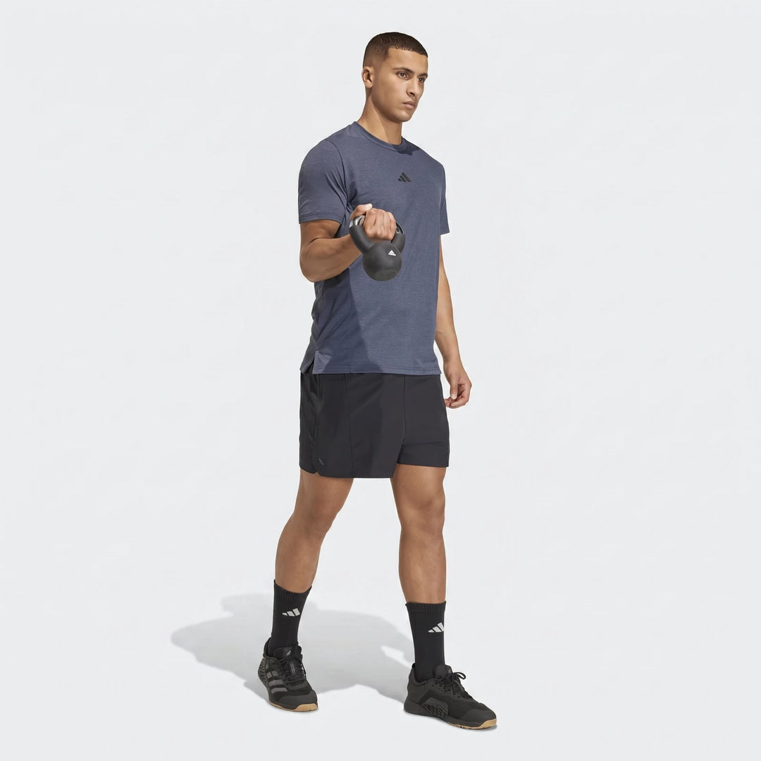 Athletic man wearing a blue adidas D4T short-sleeve t-shirt and black shorts, holding a kettlebell.
