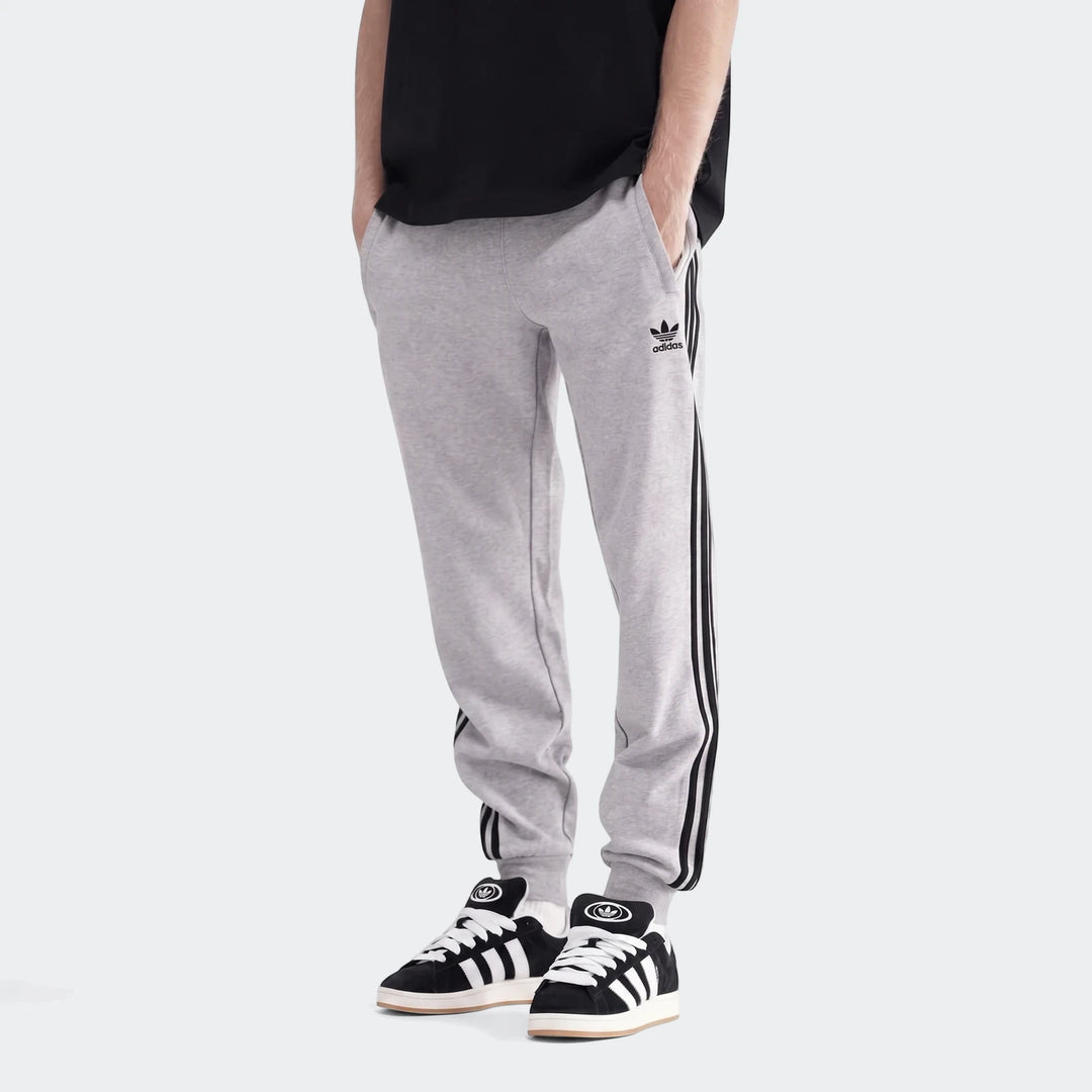 Men's grey Adidas 3-Stripes sweatpants with black and white sneakers, styled casually on a model.