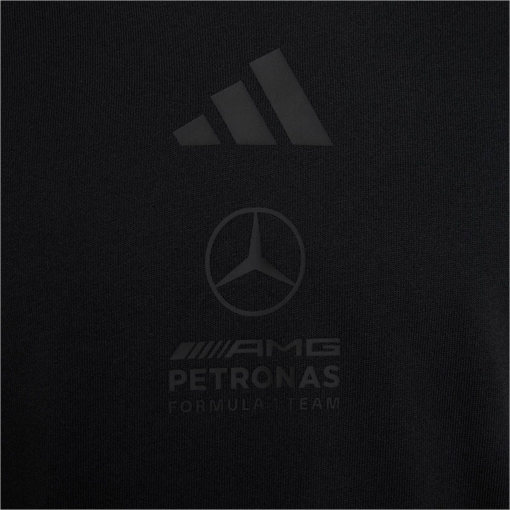 Close-up of a black Adidas Mercedes-AMG Petronas Formula 1 Team Night T-Shirt, showing the embossed logos and fabric texture.