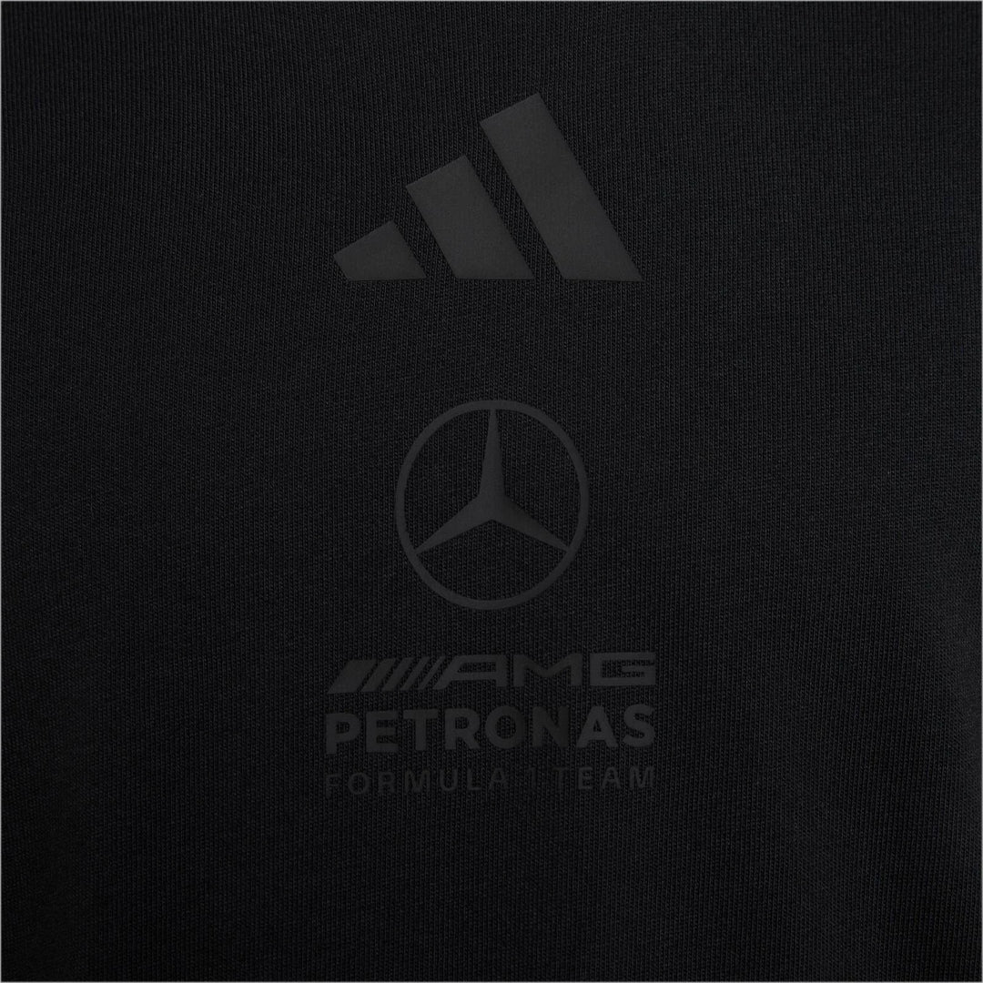 Close-up of a black Adidas Mercedes-AMG Petronas Formula 1 Team Night T-Shirt, showing the embossed logos and fabric texture.