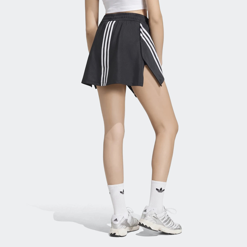 Rear view of a model wearing a black Adidas X Mia Marquez mini skirt with white stripes, paired with white socks and
