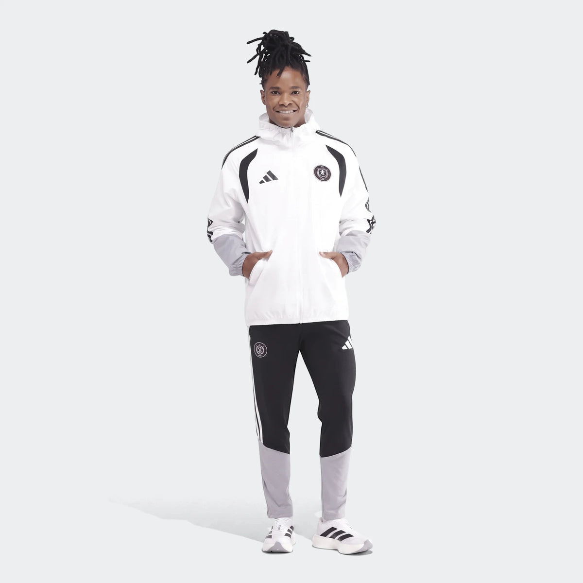 Men's white, black, and grey Adidas Op Tiro26C All Weather Jacket and matching track pants on a model, full body.