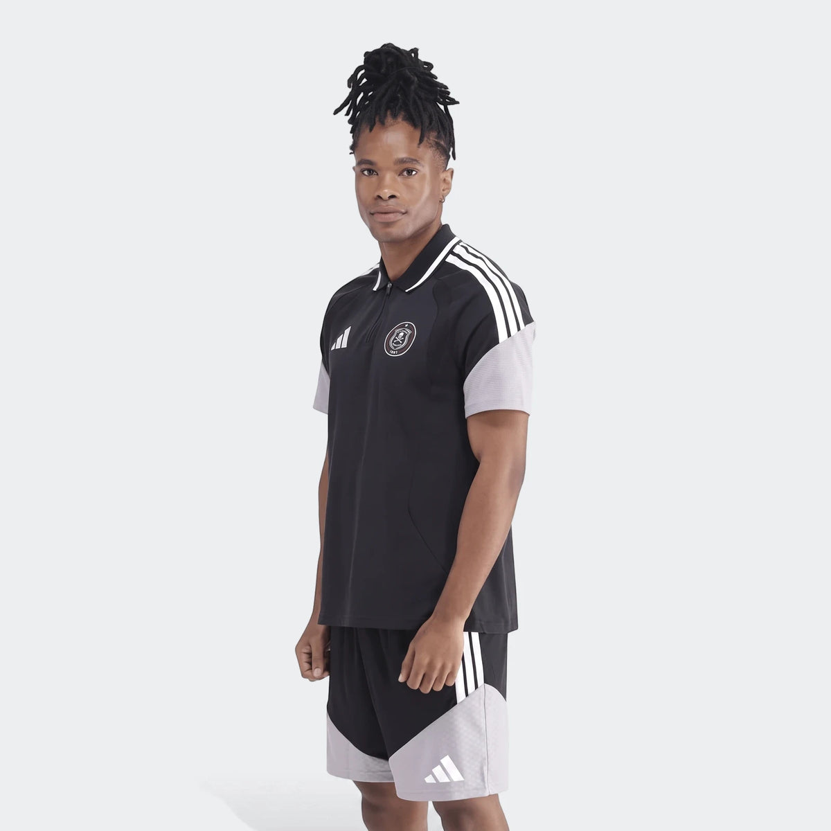 Male model wearing a black and gray Adidas Op Tiro26C Polo shirt and matching shorts, shown in a full body view.
