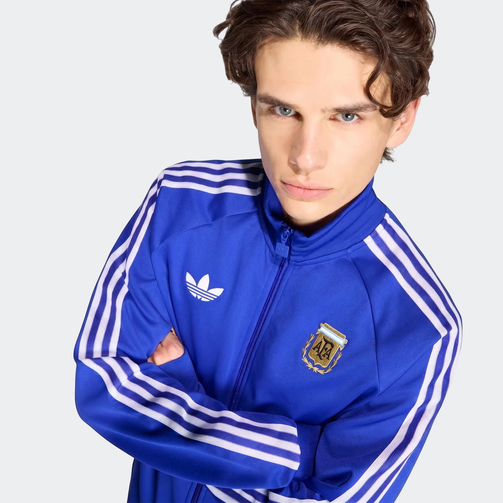 Male model wearing blue Adidas Originals Argentina track top with white stripes and AFA crest, shown from the waist up with