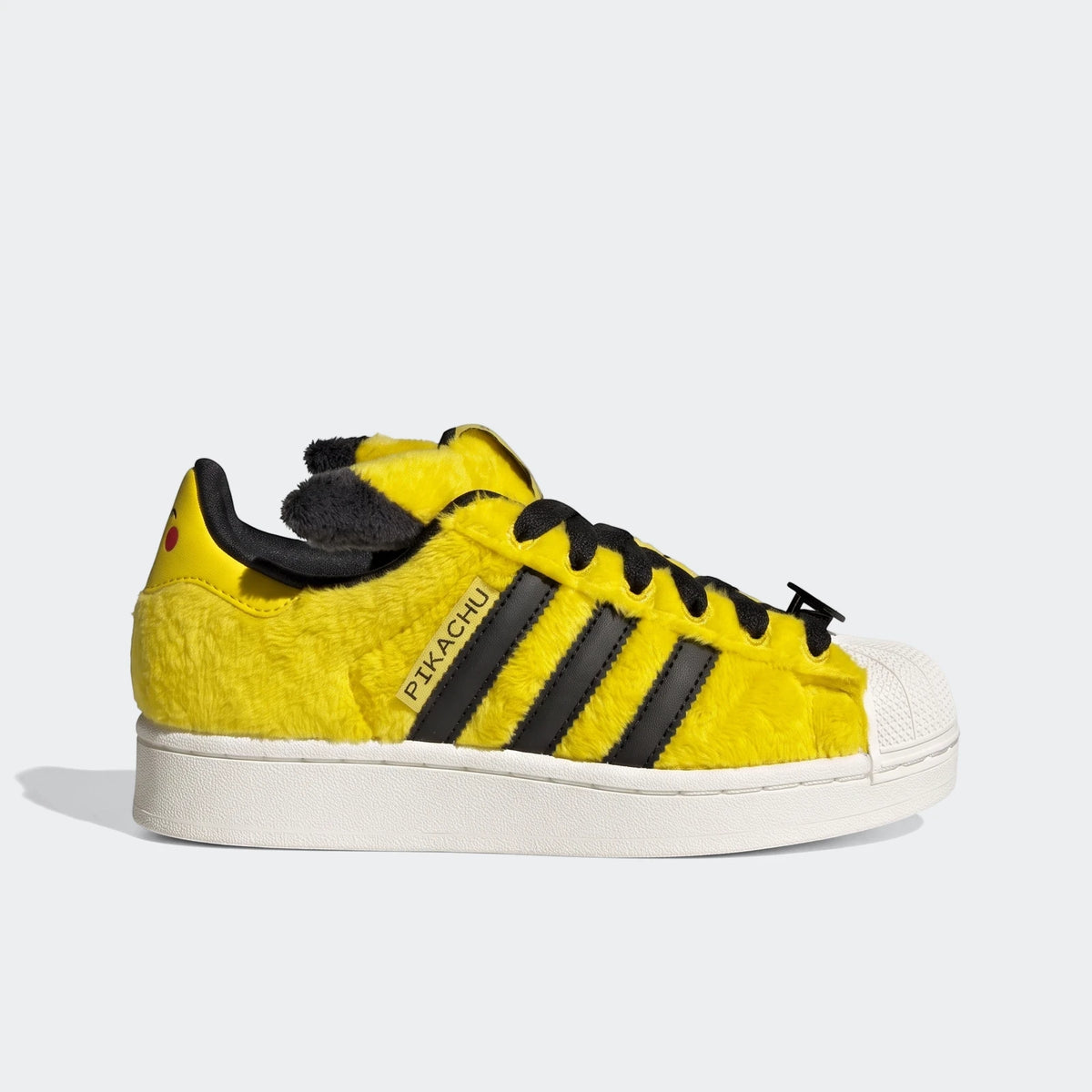 Yellow furry Adidas Pokémon Superstar II shoes with black stripes, white shell toe, and Pikachu ear details, viewed from the