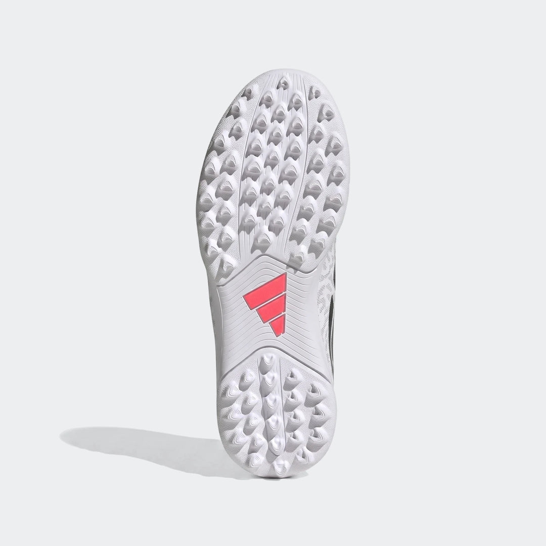 White and black Adidas Predator Club Kids' Turf Football Boots, showing the studded sole from below.