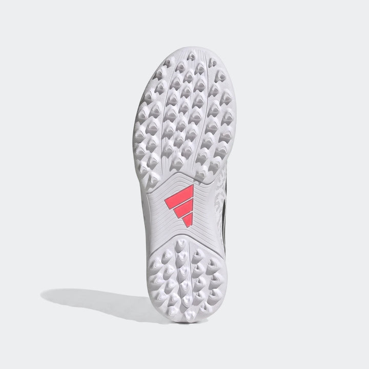 White and black Adidas Predator Club Kids' Turf Football Boots, showing the studded sole from below.