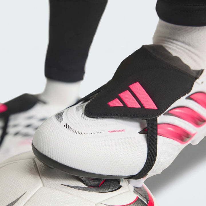 Close-up of white and pink Adidas Predator League Fold-Over Tongue Firm Ground Football Boots worn on a foot, resting on a