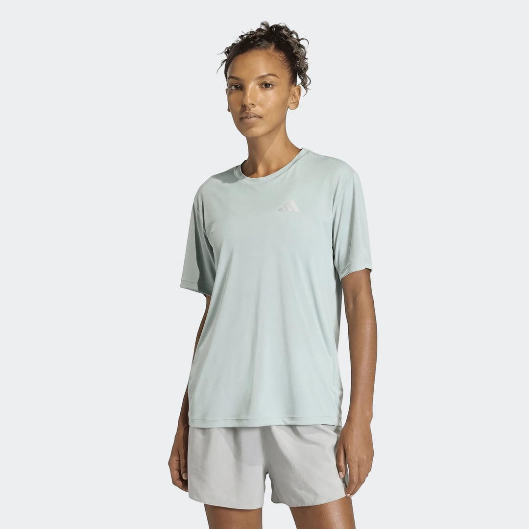 Female model wearing a light mint green Adidas Run Essentials T-shirt and light grey shorts, front view.