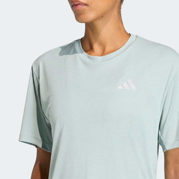 Close-up of model wearing a light blue-green Adidas Run Essentials T-Shirt with white logo.
