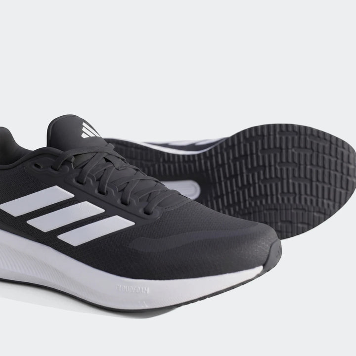 Pair of black Adidas Runfalcon 5 sneakers with white stripes and Cloudfoam midsole, positioned on a concrete surface.