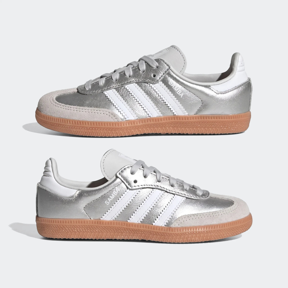 Pair of Adidas Samba OG sneakers in metallic silver with light grey suede accents and gum rubber soles, shown from a side