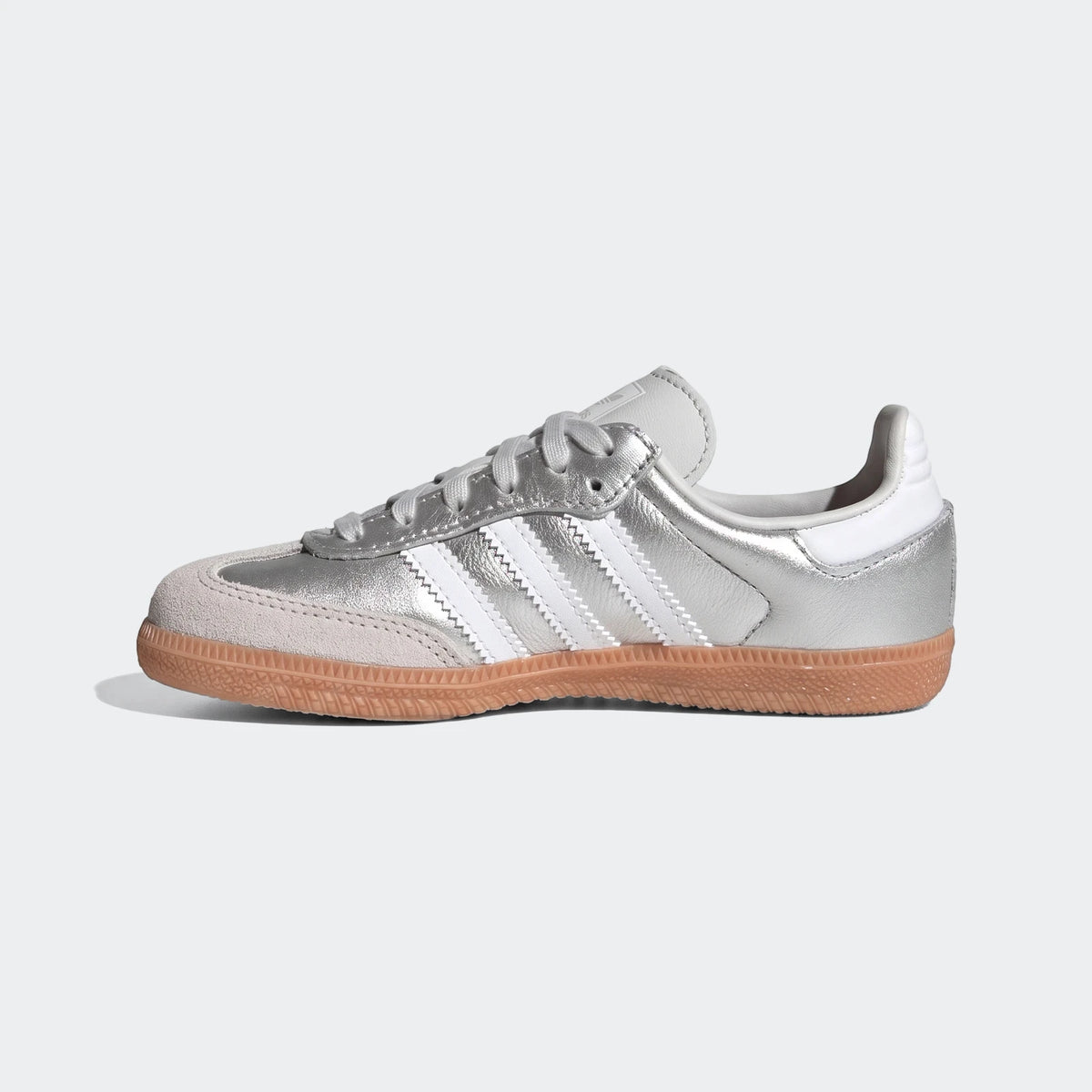 Silver Adidas Samba OG shoes with iconic white stripes, a grey suede toe, and a classic gum sole, viewed from the side.