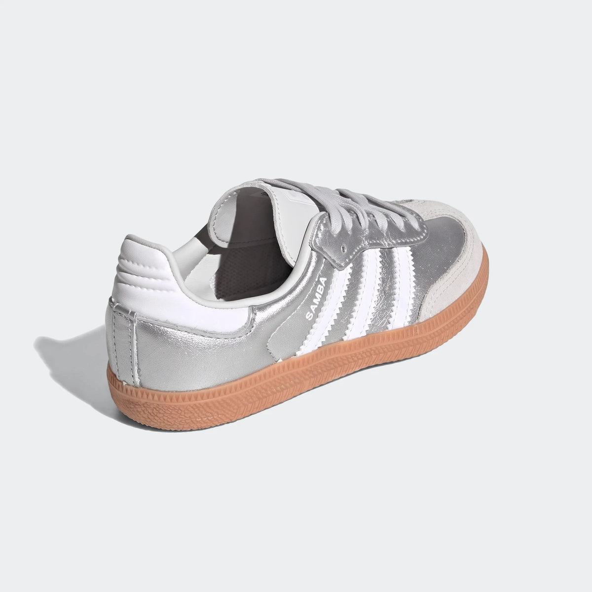 Silver Adidas Samba Og shoes with white stripes and a gum sole, shown from a rear-three-quarter view.