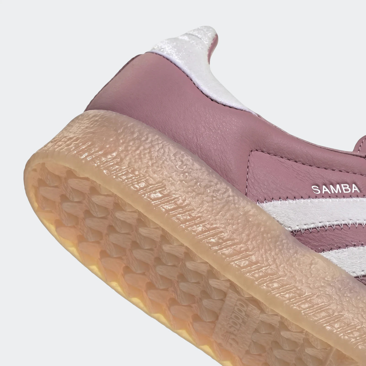 Close-up of an Adidas Sambae shoe in mauve with white stripes and a translucent gum sole, showing the heel and side view.