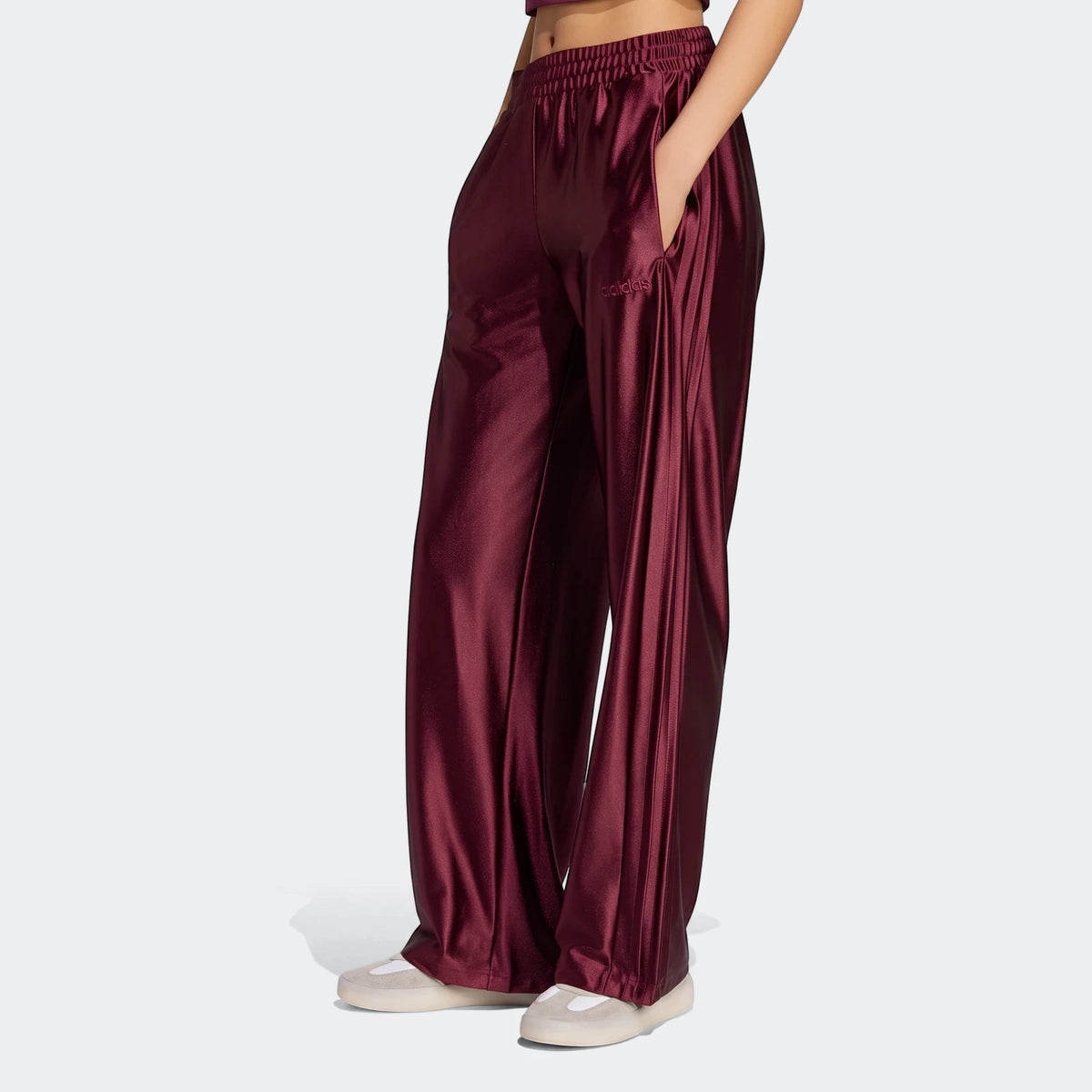Maroon Adidas Seasonal Essentials Satin Tracksuit Bottoms worn by a person from a side view, featuring an elasticated waist,