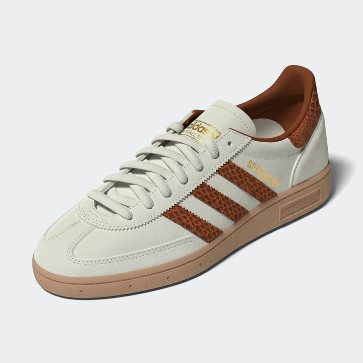 Adidas Spezial sneaker in cream white with brown snake-print stripes and a gum sole, shown from an angled view.