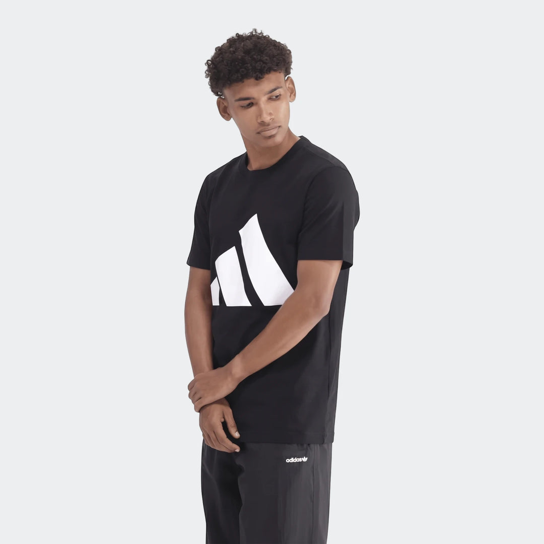 Male model wearing a black Adidas Sportswear Badge Of Sport T-Shirt with a large white logo and black athletic pants. Front