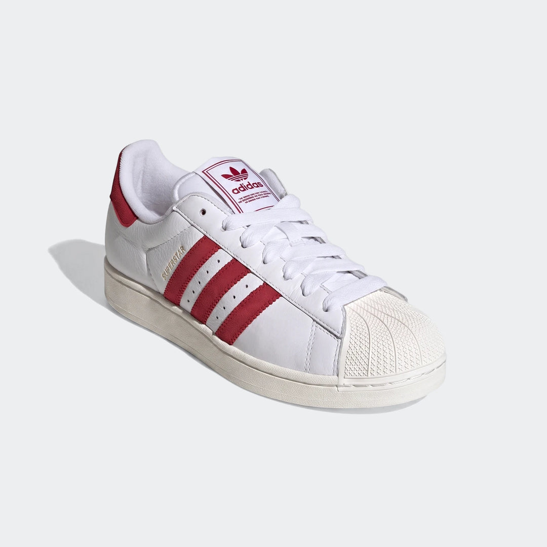 White Adidas Superstar II shoes with bold red stripes, a signature shell toe, and white laces, presented on a clean
