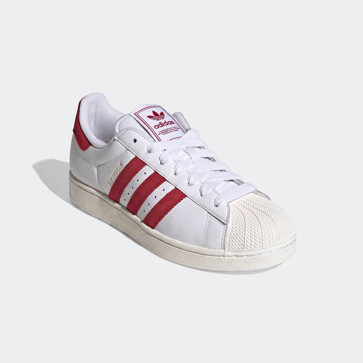 White Adidas Superstar II shoes with bold red stripes, a signature shell toe, and white laces, presented on a clean