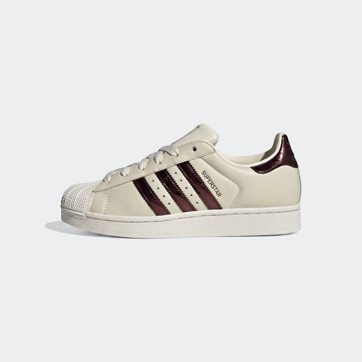 A single cream Adidas Superstar II shoe with metallic burgundy three stripes and heel tab, white laces, and a classic shell