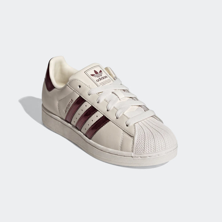 Adidas Superstar II shoes in off-white with maroon stripes and iconic shell toe, shown from an angled view.