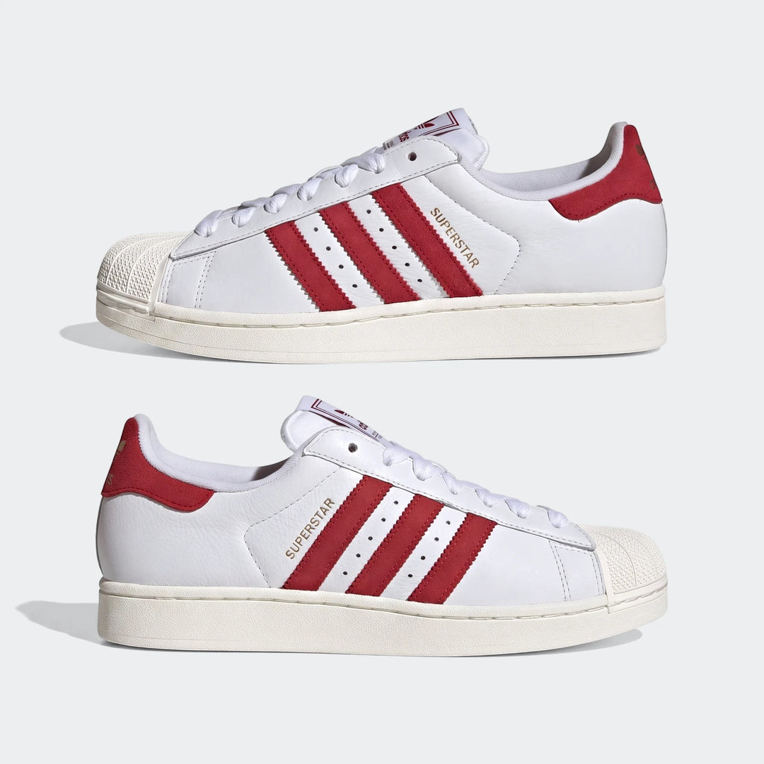 Two white Adidas Superstar II shoes with red stripes, white shell toes, and white laces, shown in a side view.