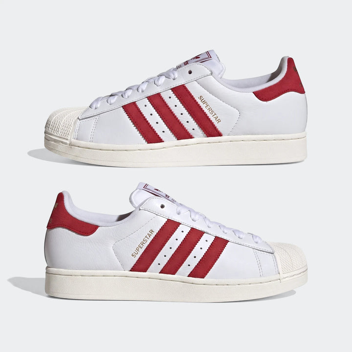 Two white Adidas Superstar II shoes with red stripes, white shell toes, and white laces, shown in a side view.