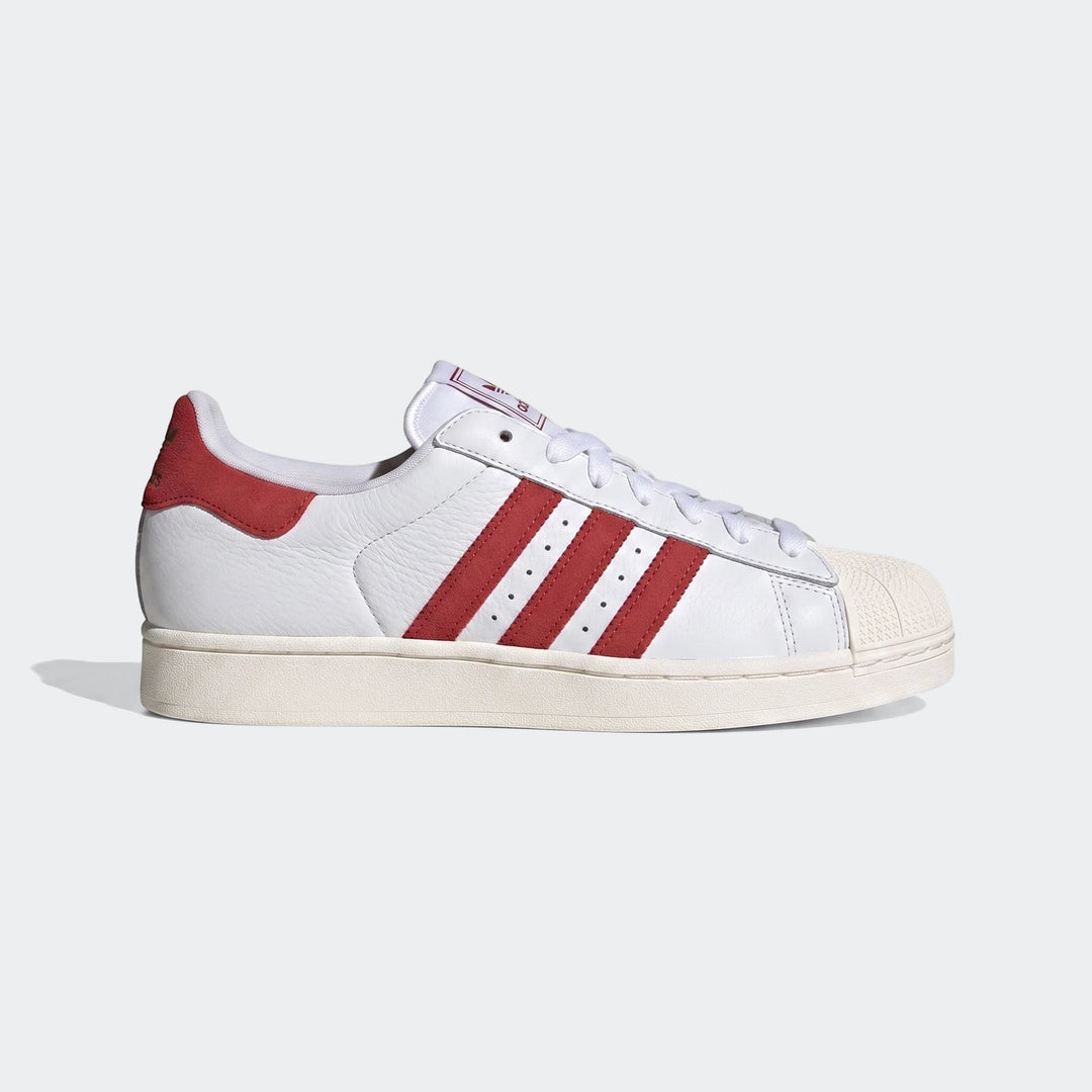 White and red Adidas Superstar II classic sneakers, featuring iconic three stripes and a shell toe, viewed from the side.