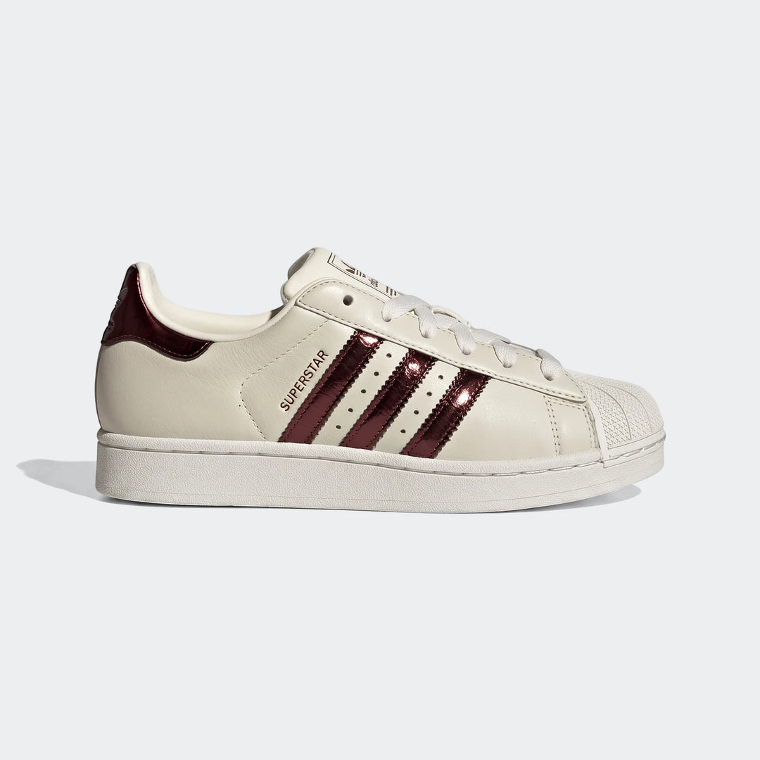 Adidas Superstar II women's shoes in cream leather with metallic maroon three stripes and shell toe, side view.