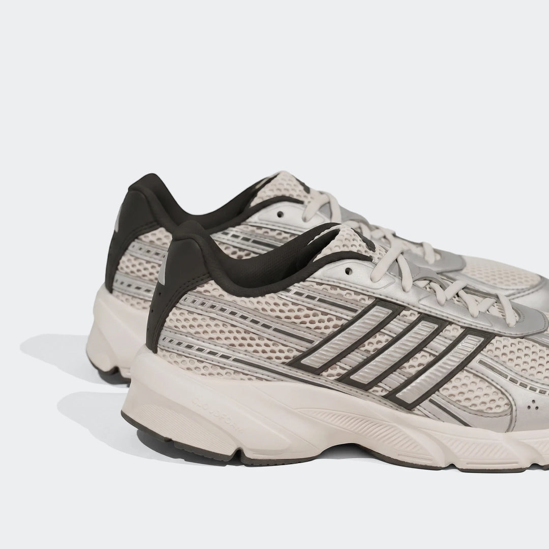 Grey and white Adidas Technochaos 2000 athletic shoes with mesh details and black accents, captured in a studio setting.