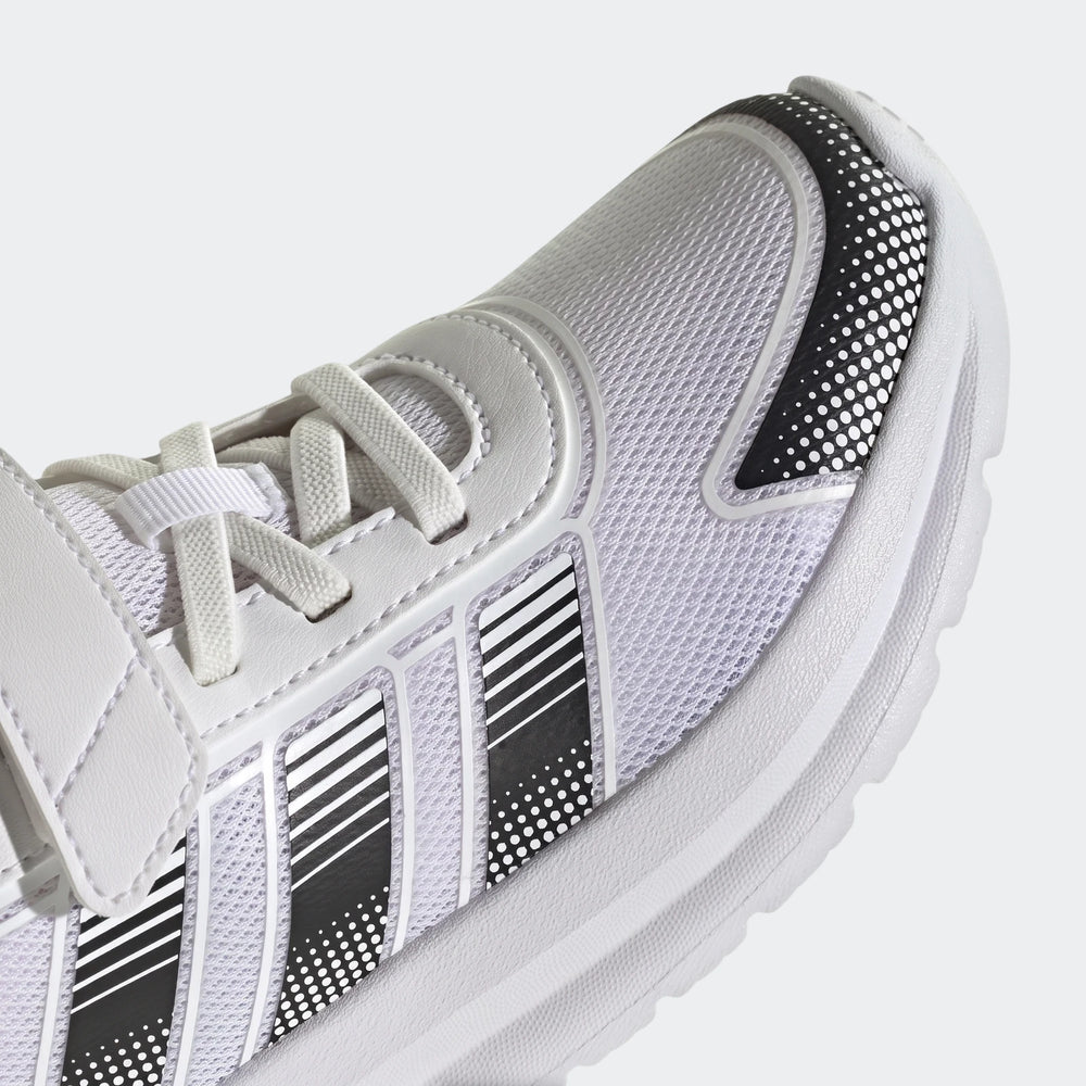 Close-up of a white Adidas Tensaur Run 4.0 children's shoe with black and white striped accents and white laces, shown from