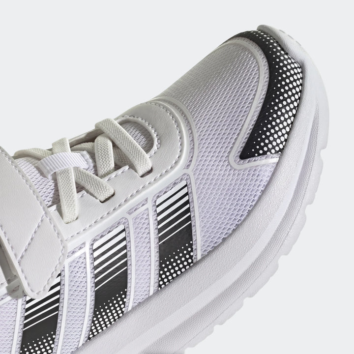 Close-up of a white Adidas Tensaur Run 4.0 children's shoe with black and white striped accents and white laces, shown from