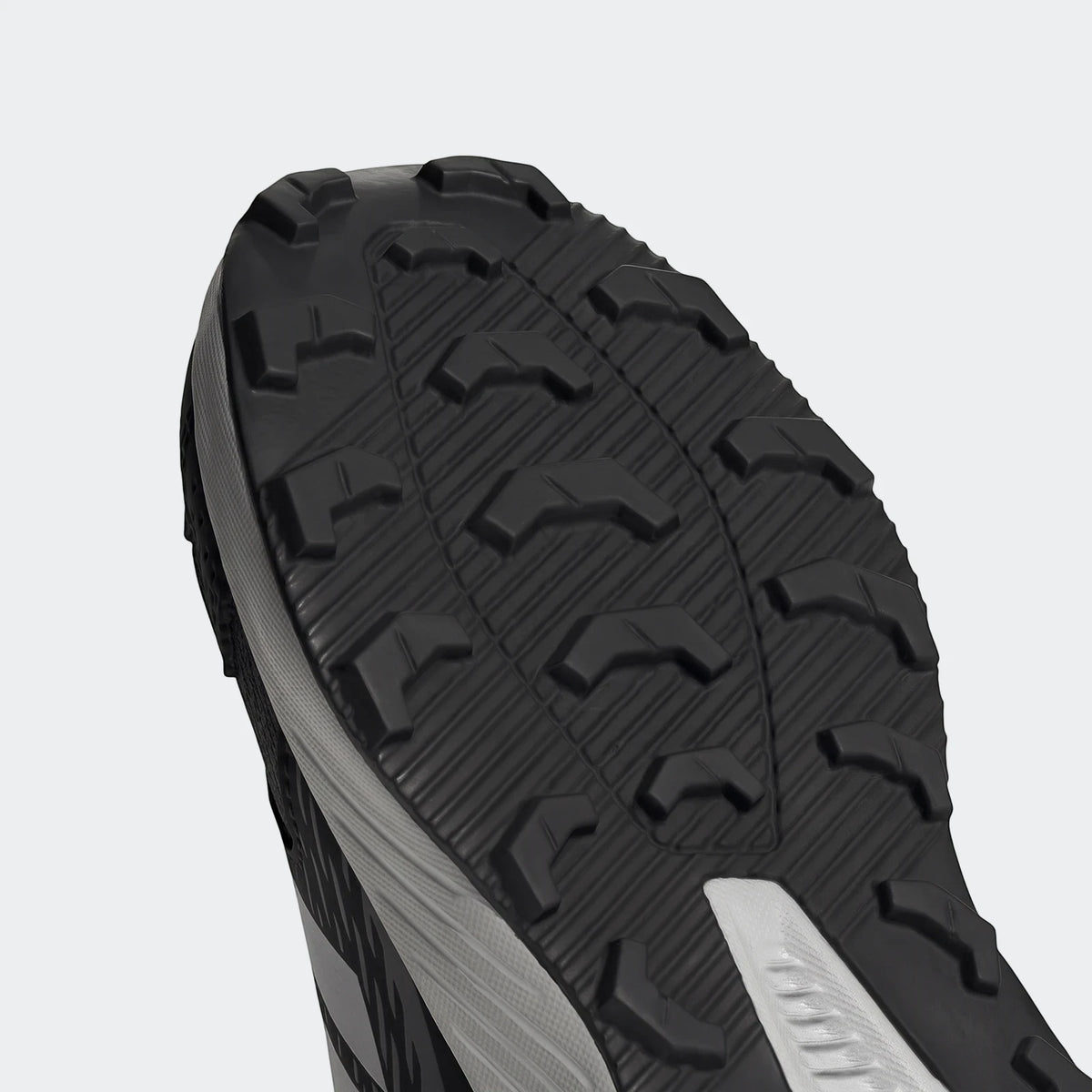 Close-up view of the black and grey sole of an Adidas Terrex Tracefinder athletic shoe, showcasing its durable tread pattern.