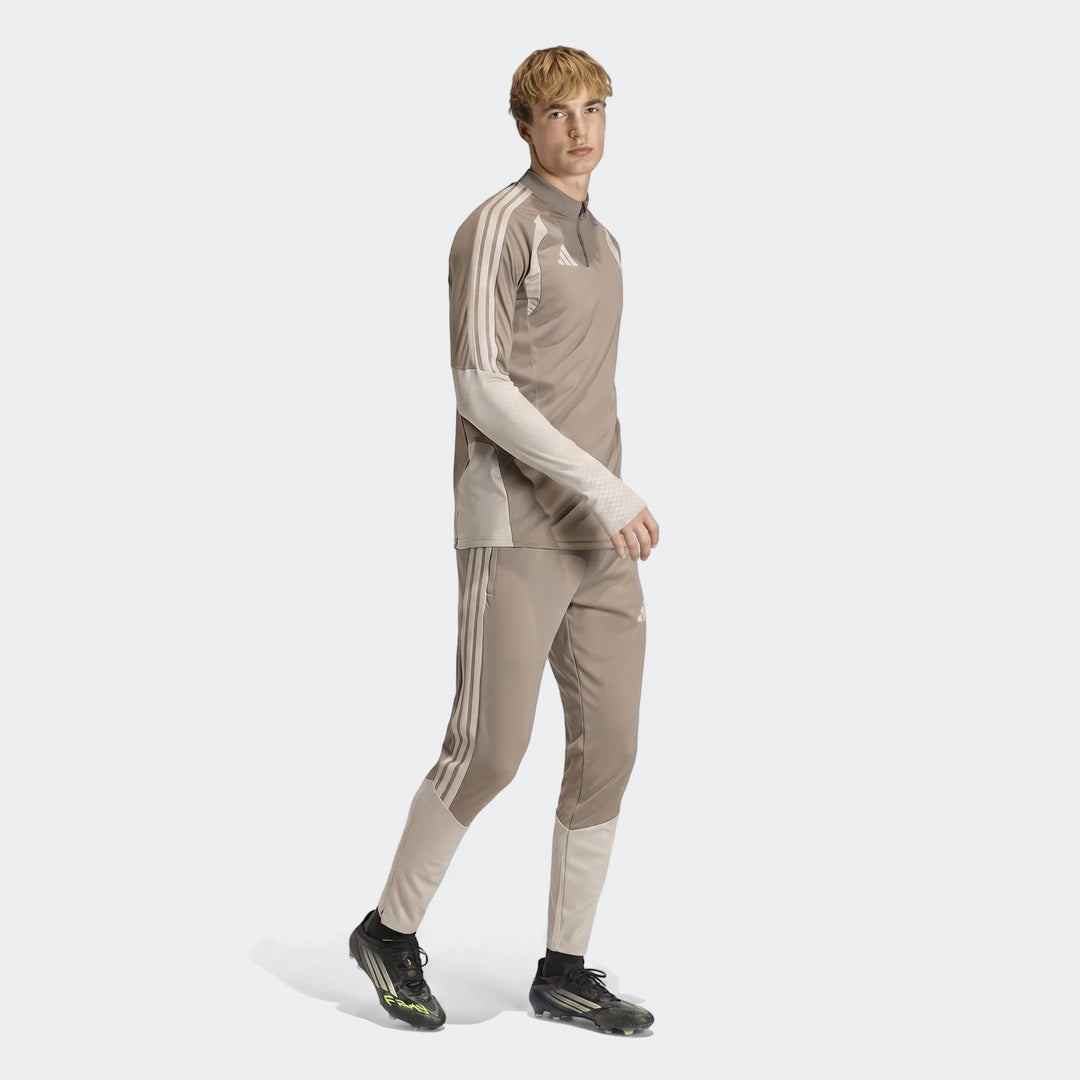 Male model wearing a brown Adidas Tior26C pant and matching athletic top, with three stripes detail, in a full body view.