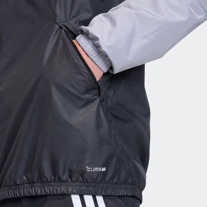 Close-up of a black and gray Adidas Tiro 26 Competition All-Weather Jacket, featuring a hand in the pocket and "CLIMA 365"